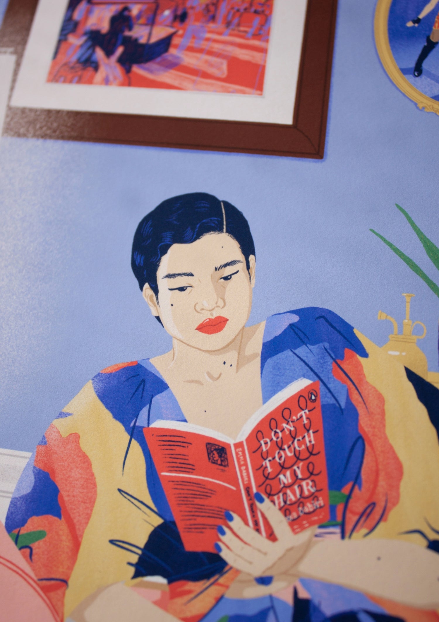 Close-up on illustration of an East Asian woman reading the book Don't Touch My Hair by Emma Dabiri. She is sat on a chaise long in her living room, surrounded by lovely objects, books and picture frames on the wall. She is wearing a multi-coloured dress.